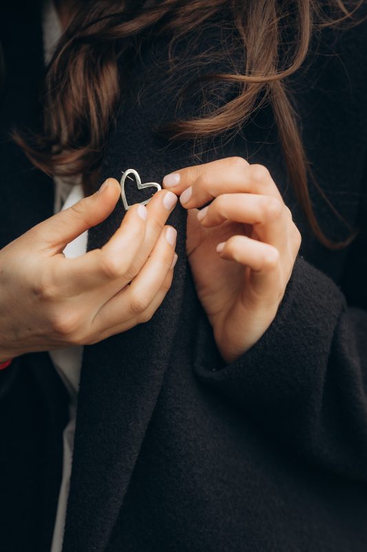 Femeie atașând broșa în formă de inimă din aur 14K, bijuterie simbolică din colecția Amour en Or Ameor