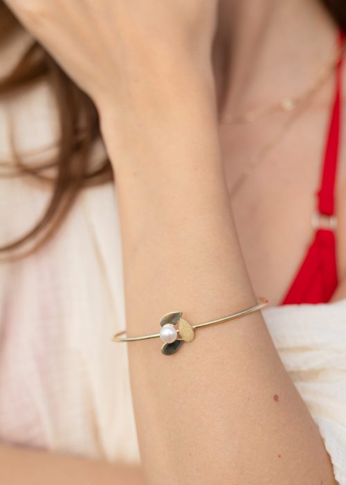Brățară fixă tip cuff din aur 14K cu perlă naturală, purtată la încheietură, design inspirat de petale, colecția Pearl AMEOR.
